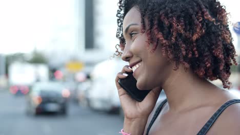 Cheerful-curly-woman-talking-with-friend-through-phone